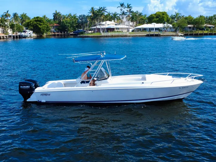  Yacht Photos Pics 2002 Intrepid 323 Cuddy boat on water, featuring Suzuki outboard motor, with scenic waterfront backdrop.