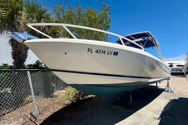  Yacht Photos Pics 2002 Intrepid 323 Cuddy boat on stands, sunny day, palm trees in background.