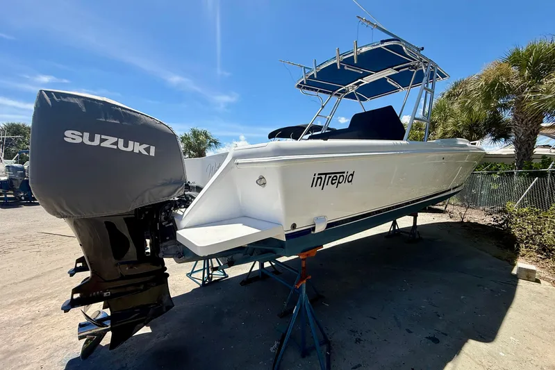  Yacht Photos Pics 2002 Intrepid 323 Cuddy boat with Suzuki outboard motor on stands, sunny day.