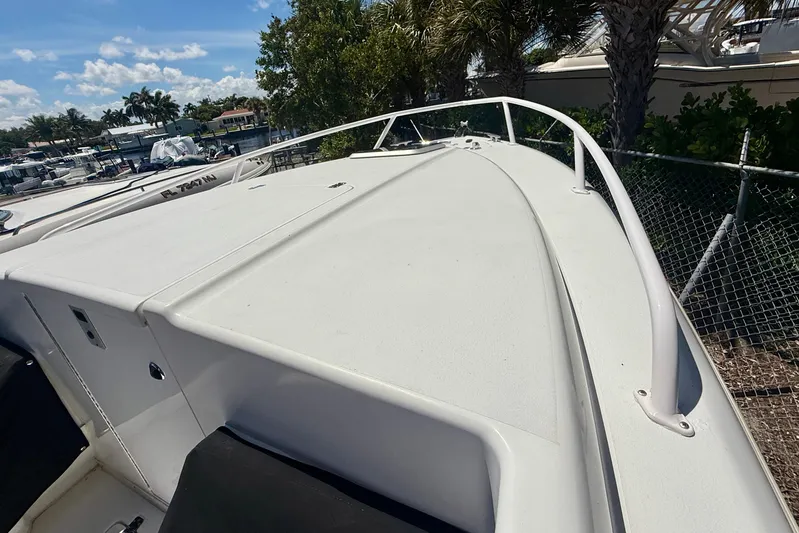  Yacht Photos Pics 2002 Intrepid 323 Cuddy boat deck with railing, docked near palm trees.