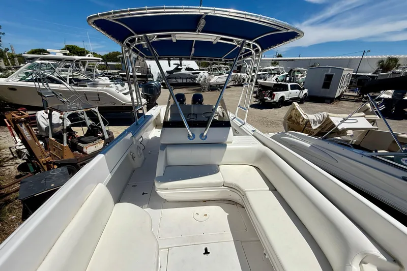  Yacht Photos Pics 2002 Intrepid 323 Cuddy boat with blue canopy, docked in a marina under clear skies.