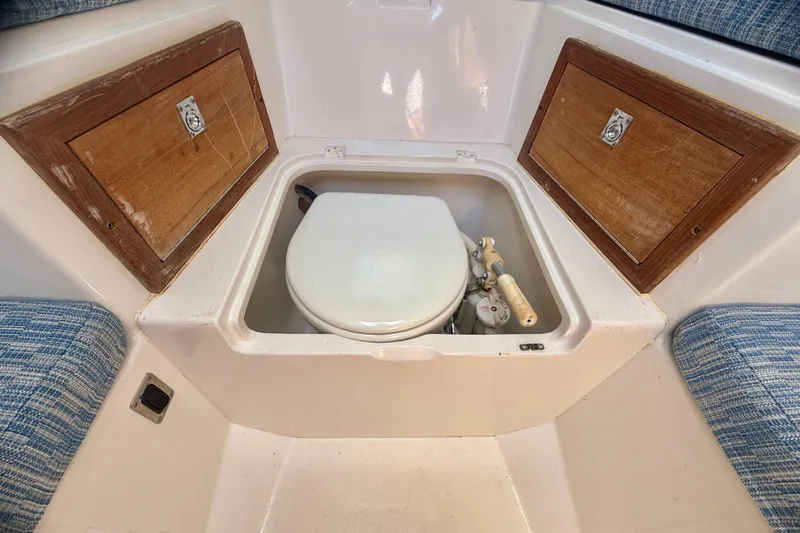  Yacht Photos Pics 2002 Intrepid 323 Cuddy boat interior with built-in toilet and wooden storage compartments.