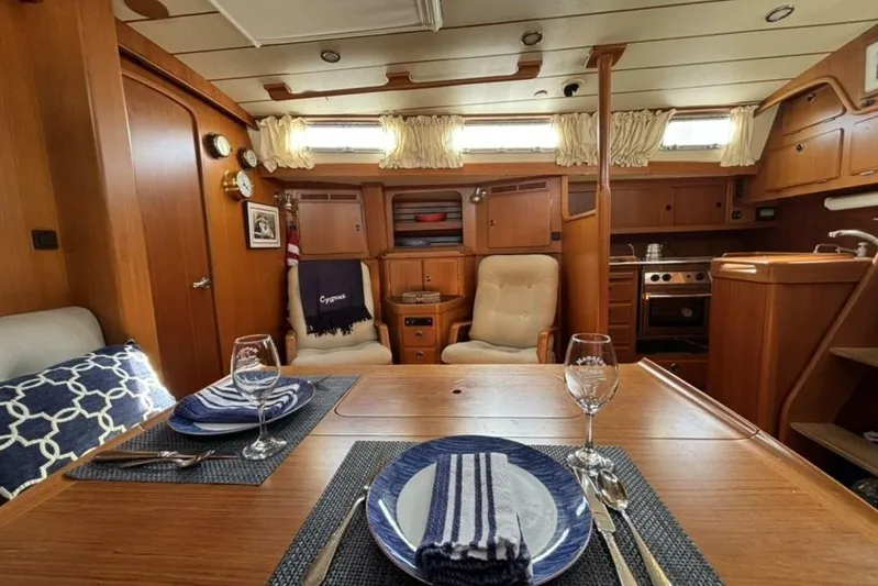 Cygnus Yacht Photos Pics Interior of 2000 Hallberg-Rassy 46 yacht, featuring elegant dining area and cozy seating.