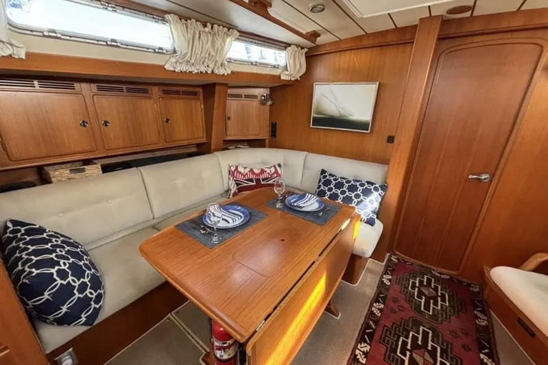 Cygnus Yacht Photos Pics Interior of 2000 Hallberg-Rassy 46 yacht with cozy seating and wooden table.