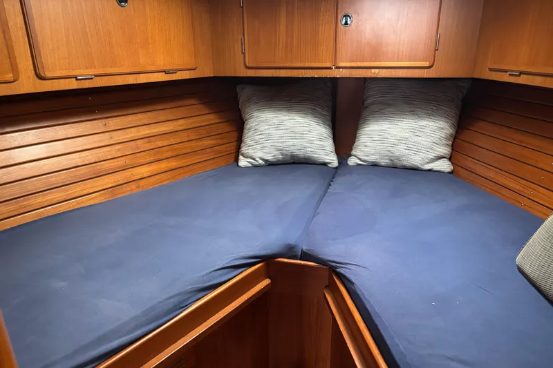 Cygnus Yacht Photos Pics Cozy cabin interior of 2000 Hallberg-Rassy 46 sailboat with blue bedding and wooden finish.