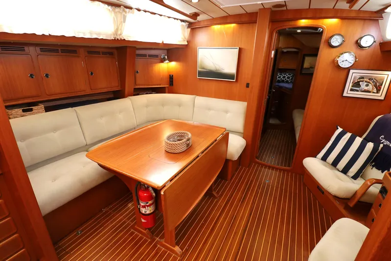 Cygnus Yacht Photos Pics Luxurious interior of 2000 Hallberg-Rassy 46 yacht with wooden furnishings and cozy seating.
