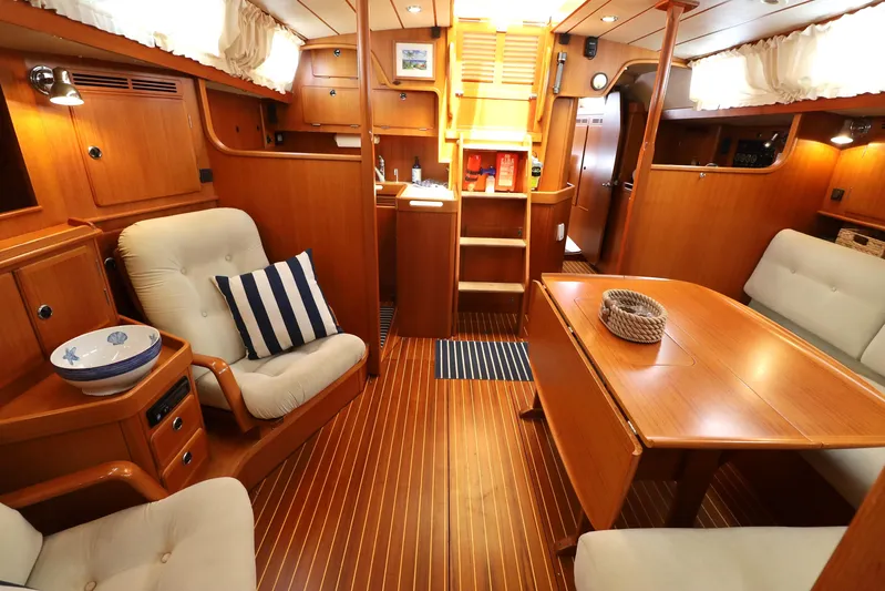 Cygnus Yacht Photos Pics Luxurious interior of 2000 Hallberg-Rassy 46 yacht with wooden furnishings and cozy seating.