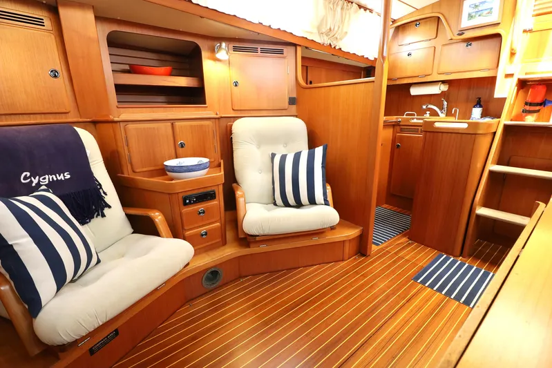 Cygnus Yacht Photos Pics Luxurious interior of 2000 Hallberg-Rassy 46 yacht with cozy seating and wooden finishes.
