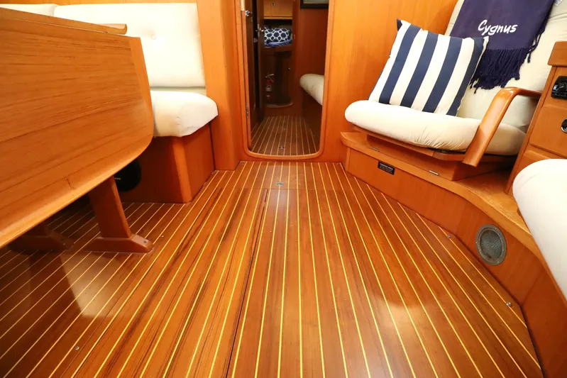 Cygnus Yacht Photos Pics Interior of 2000 Hallberg-Rassy 46 yacht with wooden flooring and cushioned seating.