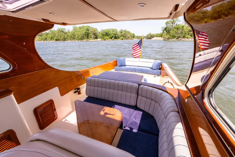 Old Fashioned Yacht Photos Pics 2002 Hinckley Picnic Boat EP interior with elegant seating and American flag on a scenic waterway.