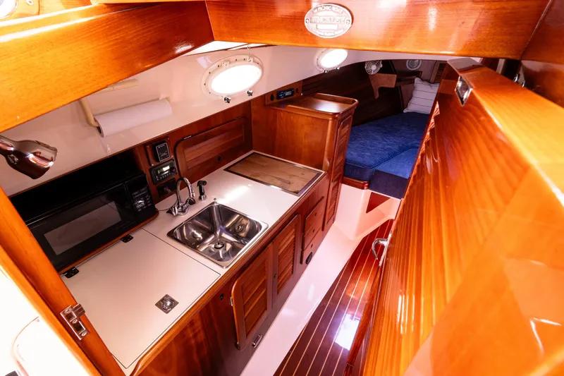 Old Fashioned Yacht Photos Pics 2002 Hinckley Picnic Boat EP interior with wood finish, kitchenette, and cozy sleeping area.