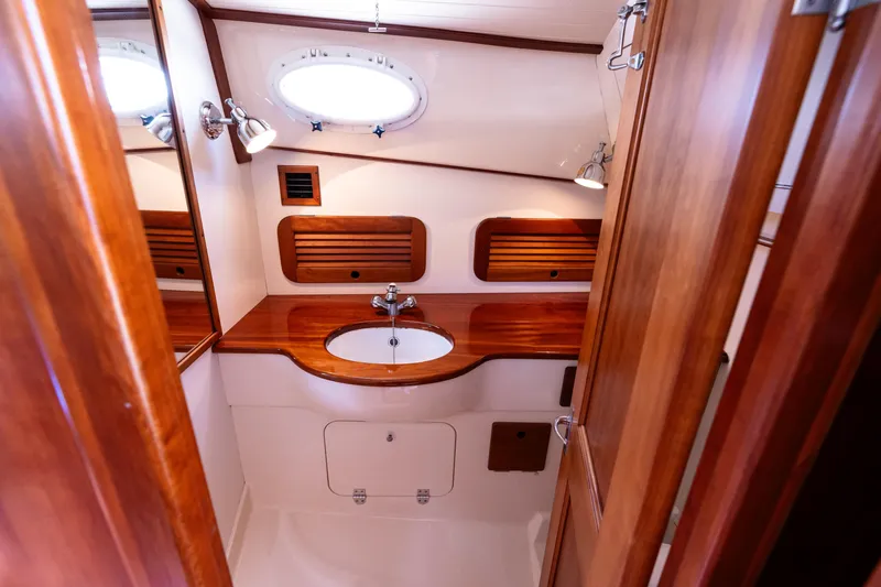 Old Fashioned Yacht Photos Pics 2002 Hinckley Picnic Boat EP bathroom with wooden cabinetry and round porthole window.