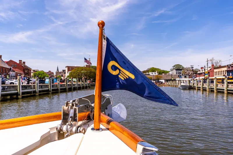 Old Fashioned Yacht Photos Pics 2002 Hinckley Picnic Boat EP on a scenic waterfront with a blue flag.