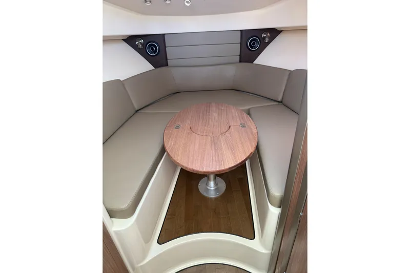  Yacht Photos Pics 2019 Boston Whaler 315 Conquest cabin interior with round wooden table and cushioned seating.