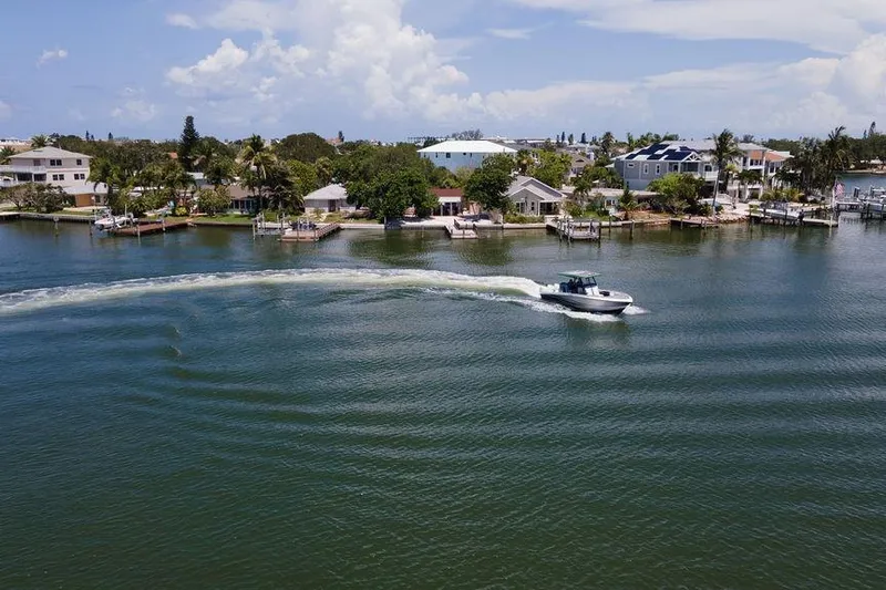  Yacht Photos Pics A 2022 Fountain 34 SC boat cruising on a scenic waterfront with houses and docks.