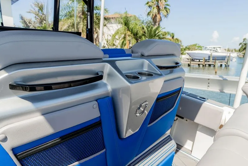 Yacht Photos Pics 2022 Fountain 34 SC boat interior with blue and gray seating, cup holders, and waterfront view.