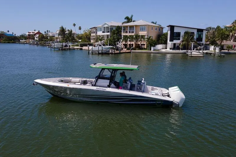  Yacht Photos Pics 2022 Fountain 34 SC boat cruising near waterfront homes on a sunny day.