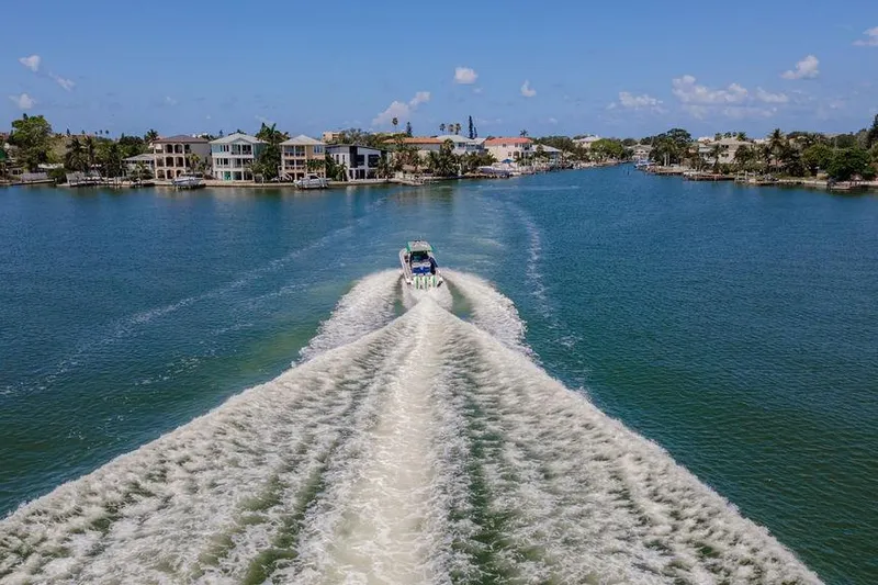  Yacht Photos Pics 2022 Fountain 34 SC boat cruising through a scenic waterway, leaving a large wake.