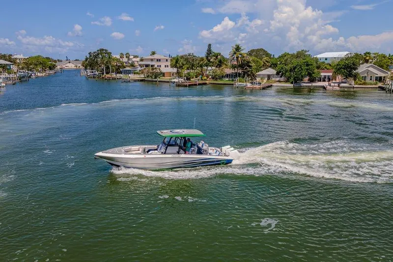  Yacht Photos Pics 2022 Fountain 34 SC boat cruising on a scenic waterway with houses and trees in the background.