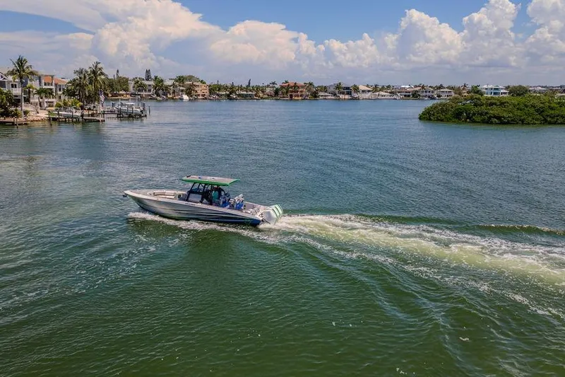  Yacht Photos Pics 2022 Fountain 34 SC boat cruising on a scenic waterway with lush surroundings.