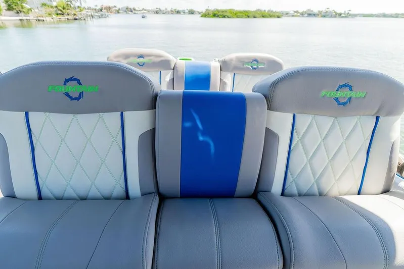  Yacht Photos Pics 2022 Fountain 34 SC boat seats with blue and gray upholstery, overlooking a serene water view.