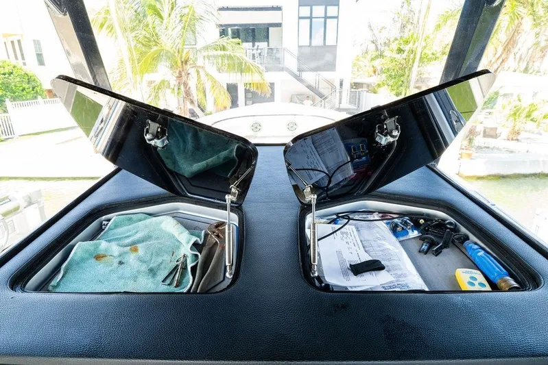 Yacht Photos Pics Open storage compartments on a 2022 Fountain 34 SC boat dashboard, with tools and documents.