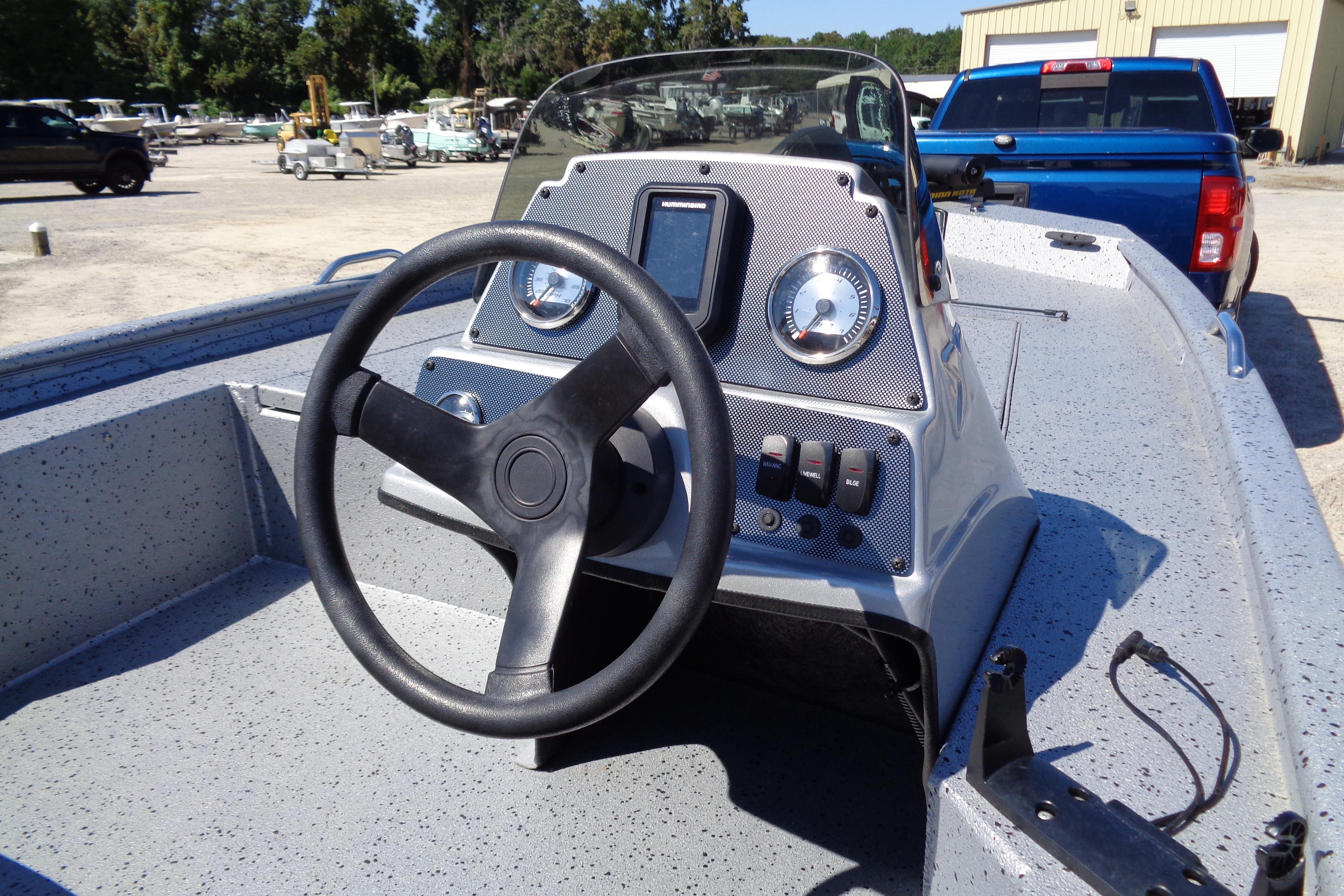 2016 Express PT175 boat dashboard with steering wheel and gauges in a marina setting.