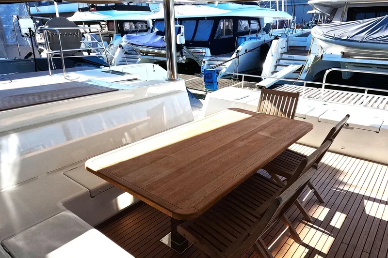  Yacht Photos Pics Outdoor dining area on 2024 Lagoon 620 NEO yacht, featuring wooden table and chairs.