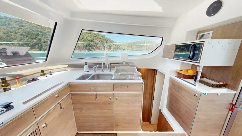 Aquatic Odyssey Yacht Photos Pics Modern kitchen interior of 2022 Bali CATSPACE yacht with wood cabinets and ocean view.