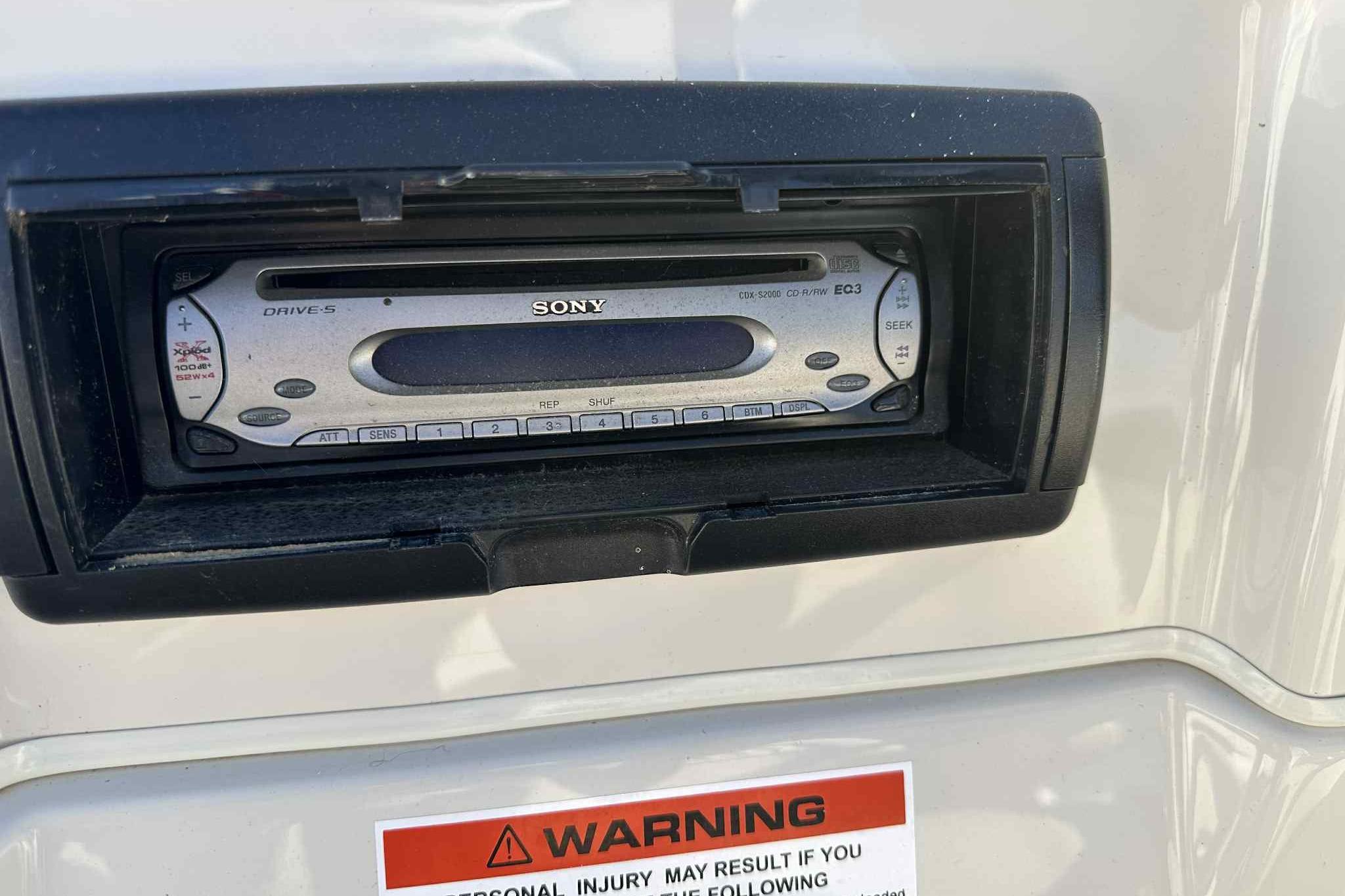 Sony car stereo in a 1993 Nova Spyder, with warning label below.