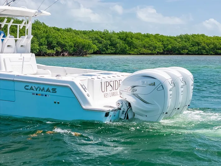 Caymas Yacht Photos Pics 2023 Caymas 401CC boat with triple Yamaha engines cruising in clear waters.