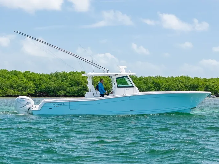 Caymas Yacht Photos Pics 2023 Caymas 401CC boat cruising on clear blue water with lush greenery in the background.