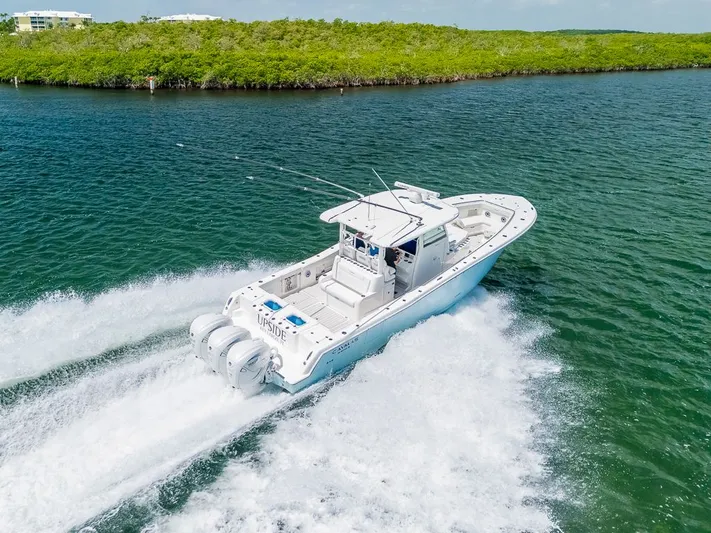 Caymas Yacht Photos Pics 2023 Caymas 401CC boat cruising on open water, surrounded by lush greenery.