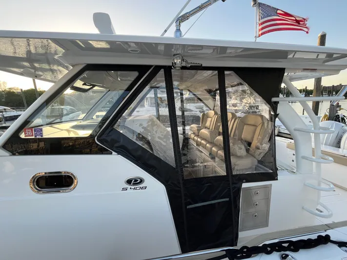  Yacht Photos Pics 2019 Pursuit S 408 Sport boat with enclosed seating area and American flag.