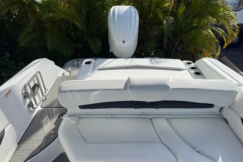  Yacht Photos Pics 2026 Four Winns HD8 OB boat interior with white seating and cup holders, surrounded by lush greenery.