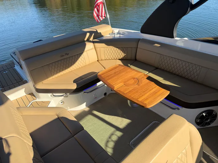  Yacht Photos Pics Luxurious seating area on 2023 Sea Ray 280 SLX boat with wooden table and American flag.