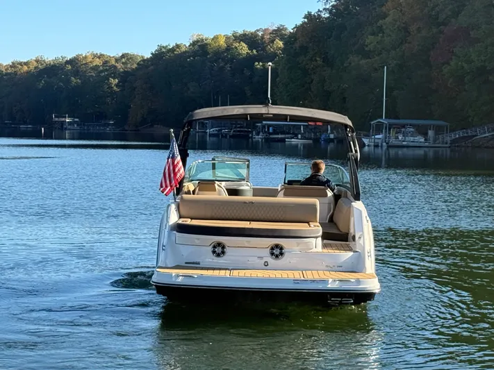  Yacht Photos Pics 2023 Sea Ray 280 SLX boat cruising on a serene lake with lush forest backdrop.
