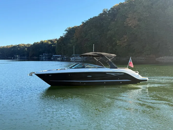  Yacht Photos Pics 2023 Sea Ray 280 SLX boat cruising on a serene lake with forested shoreline.