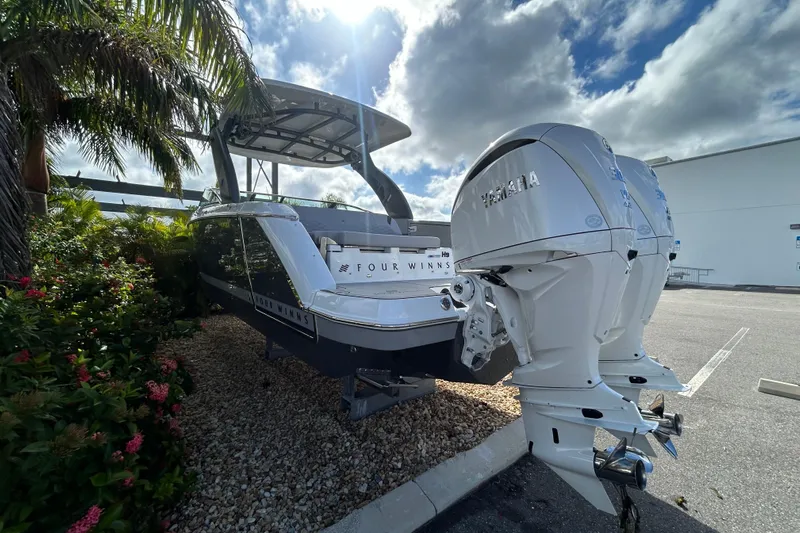  Yacht Photos Pics 2026 Four Winns H9 OB boat with dual Yamaha outboard engines, parked near tropical foliage.