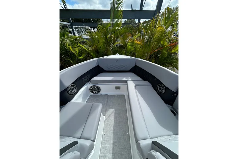  Yacht Photos Pics 2026 Four Winns H9 OB boat interior with gray seating and speakers, surrounded by lush greenery.