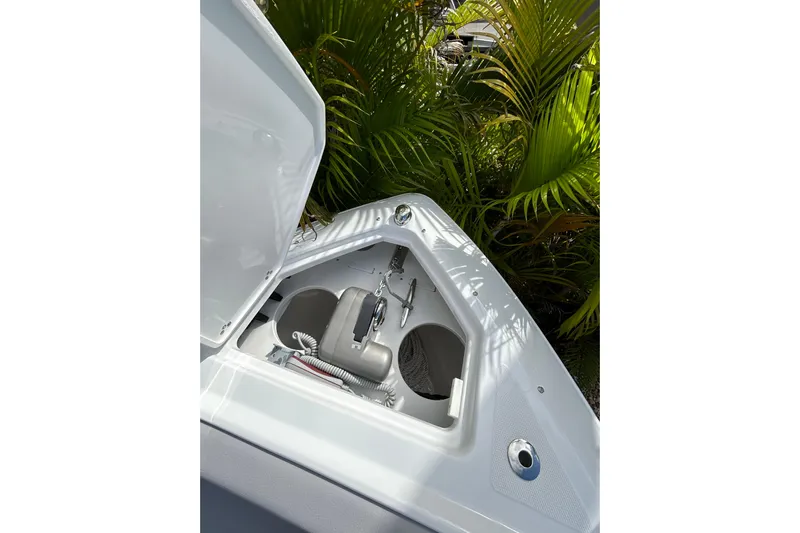  Yacht Photos Pics Open storage compartment on 2026 Four Winns H9 OB boat, surrounded by lush greenery.