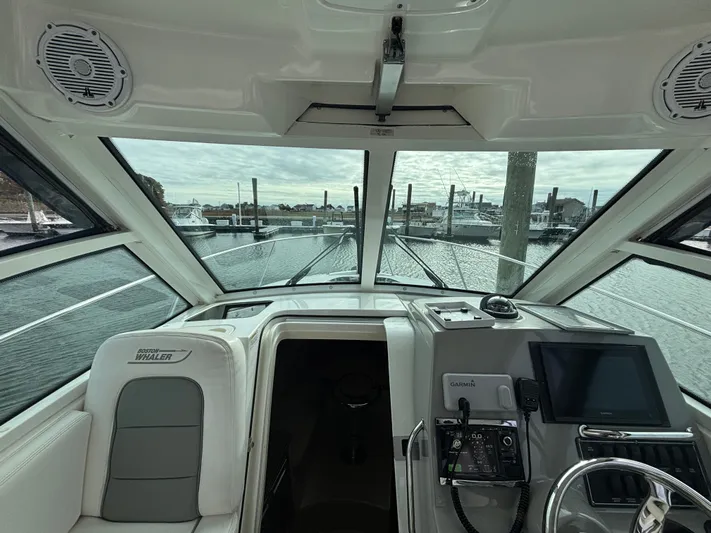  Yacht Photos Pics Interior view of 2014 Boston Whaler 285 Conquest boat with navigation equipment and marina backdrop.
