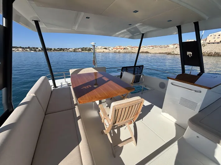 Barcajack Yacht Photos Pics Fountaine Pajot MY6 2022 yacht deck with seating and dining area, overlooking calm waters.