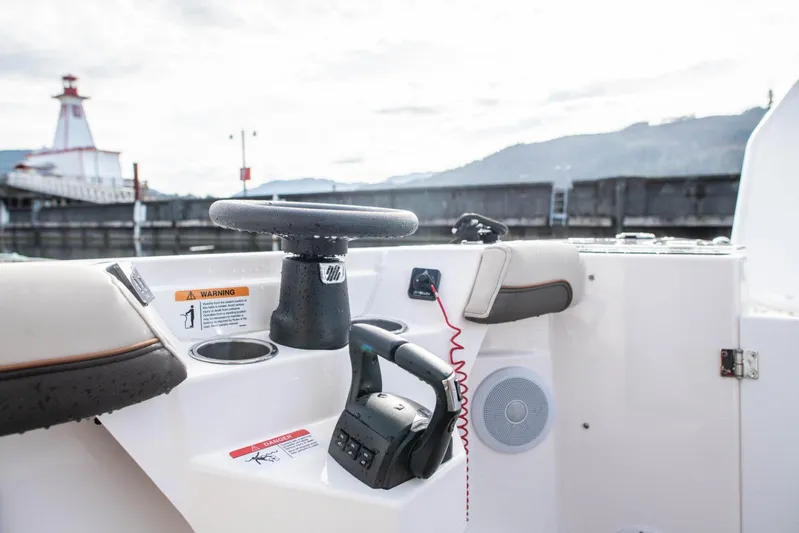  Yacht Photos Pics 2025 Cutwater C-288 Coupe helm with steering wheel and controls, docked near a lighthouse.