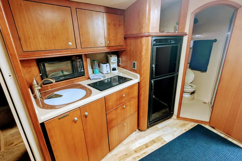  Yacht Photos Pics 2000 Cruisers Yachts 3870 Express interior kitchen with wood cabinets and appliances.