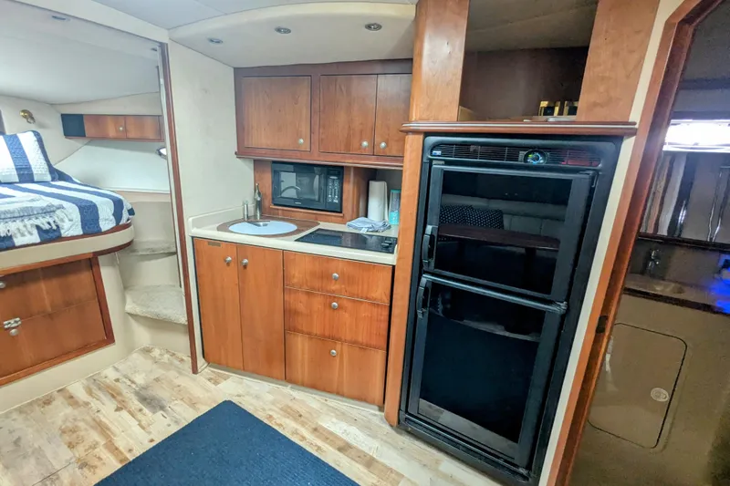  Yacht Photos Pics 2000 Cruisers Yachts 3870 Express interior with kitchenette, bed, and wooden cabinetry.