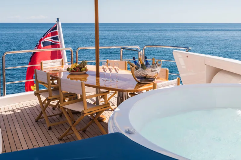 Benita Blue Yacht Photos Pics Luxury yacht deck with dining table, hot tub, and ocean view, Evolution Yachts Custom 2005.