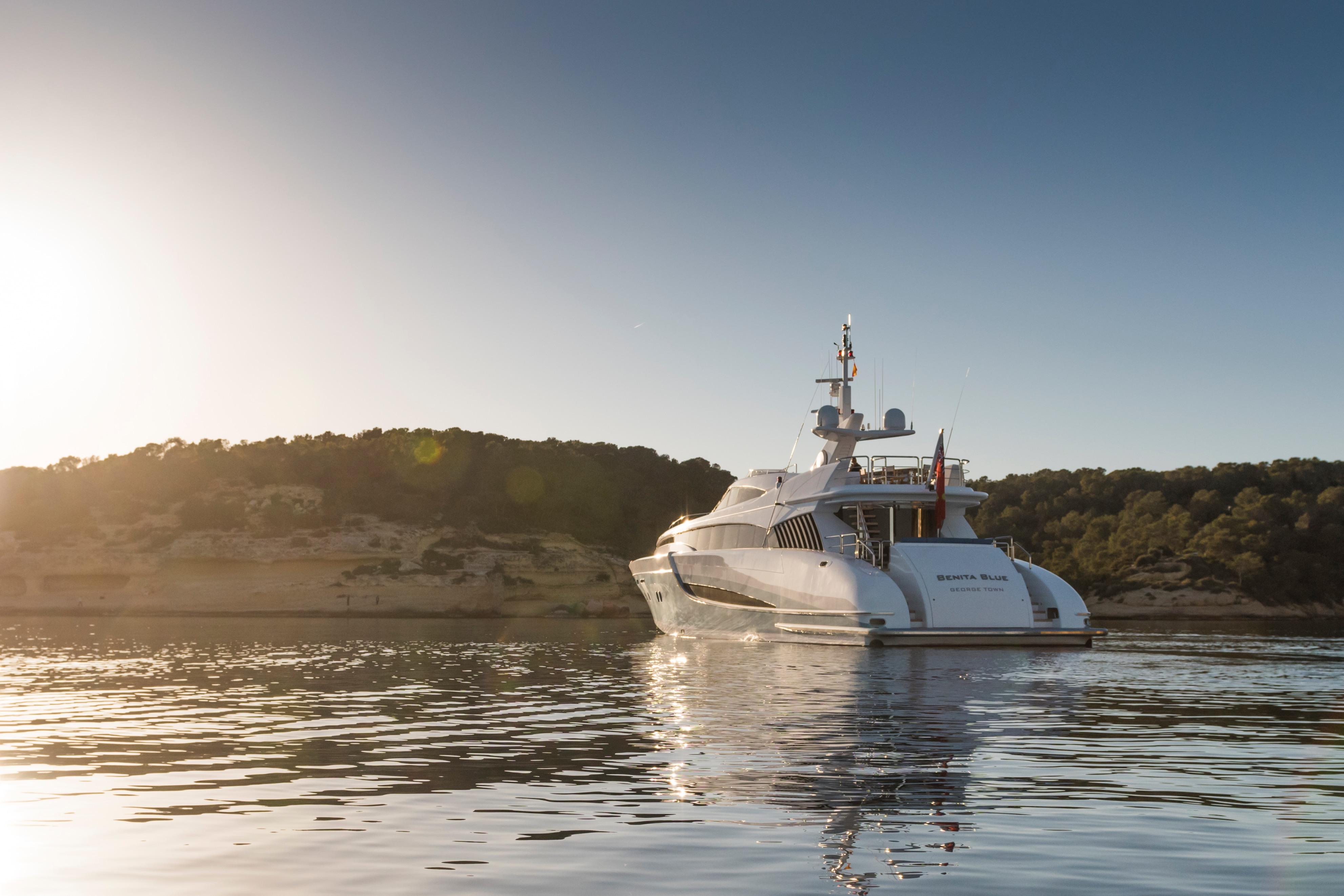 Luxurious 2005 Evolution Yachts Custom yacht cruising at sunset near scenic coastline.