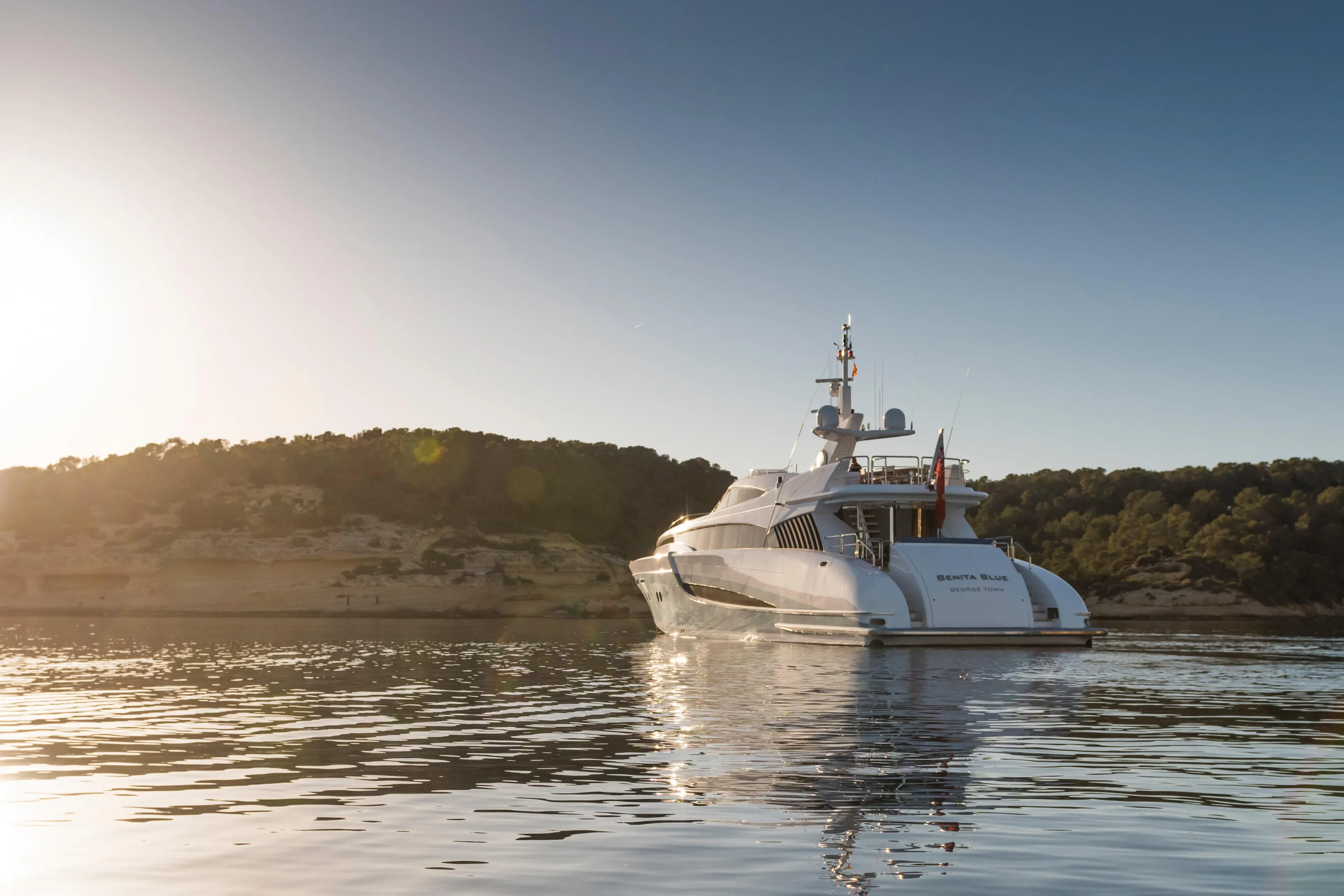 Luxurious 2005 Evolution Yachts Custom yacht cruising at sunset near scenic coastline.