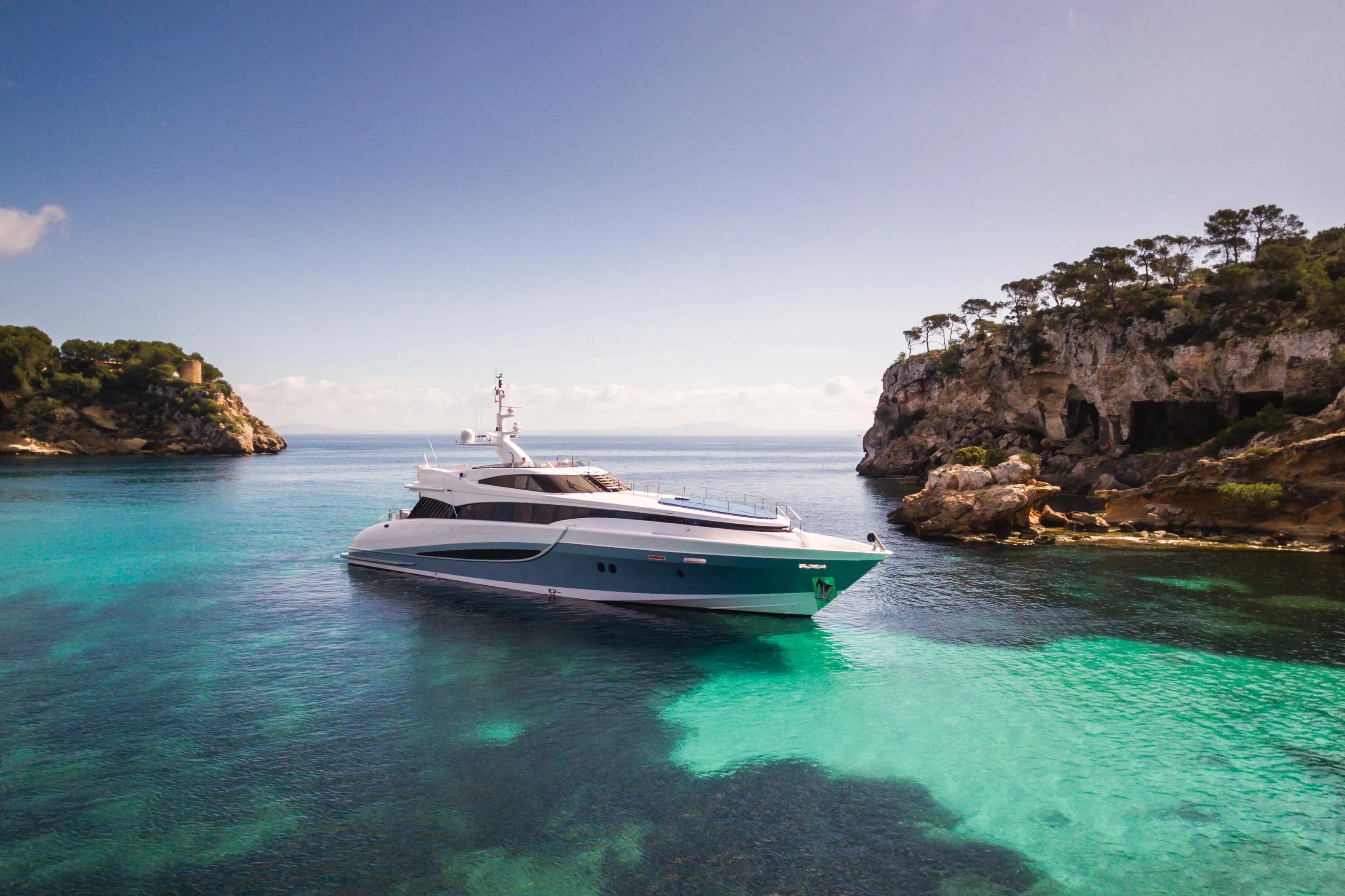 Luxurious 2005 Evolution Yachts Custom in serene turquoise waters near rocky cliffs.